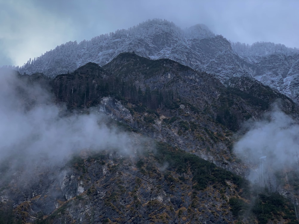 a mountain covered in fog and clouds on a cloudy day