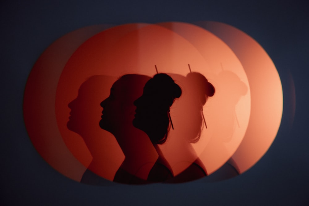 a silhouette of a woman in front of a round mirror