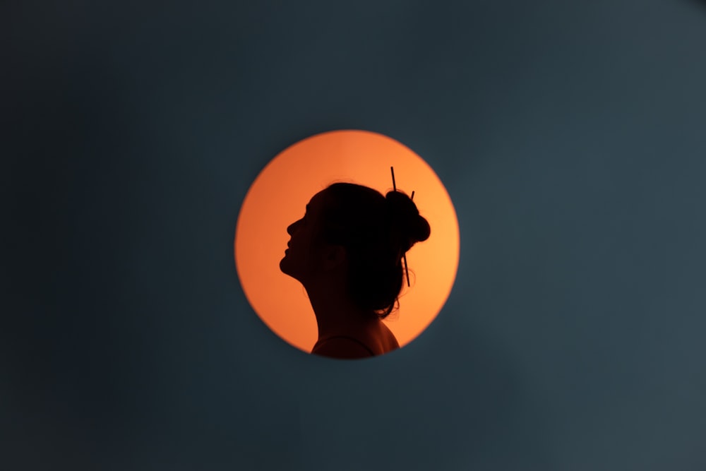 a silhouette of a woman in front of a sun