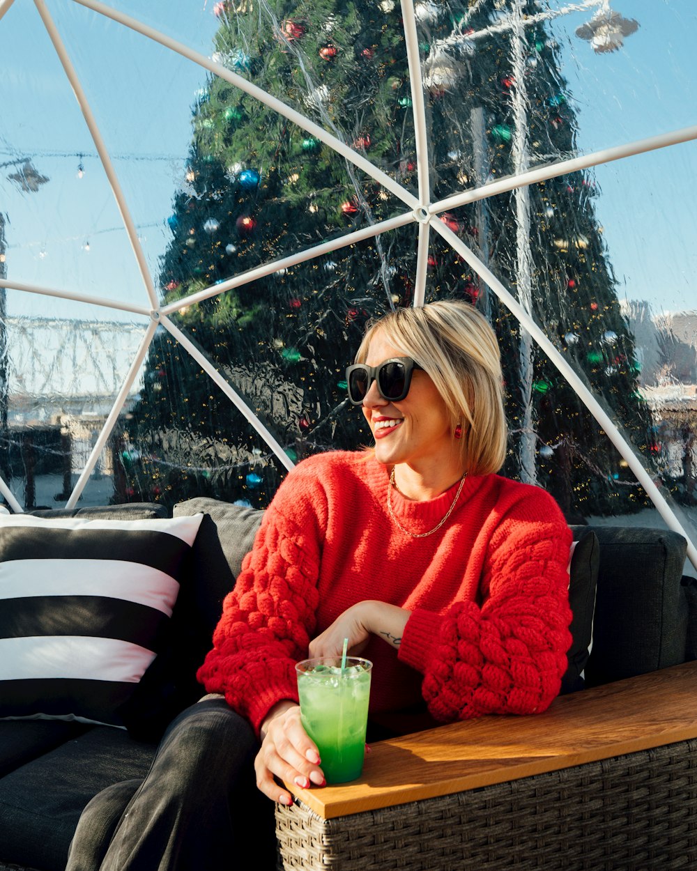 a woman sitting on a couch with a green drink