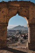a view of a city through a stone arch