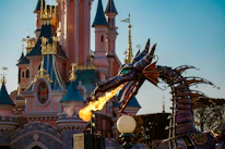 a fire breathing dragon statue in front of a castle