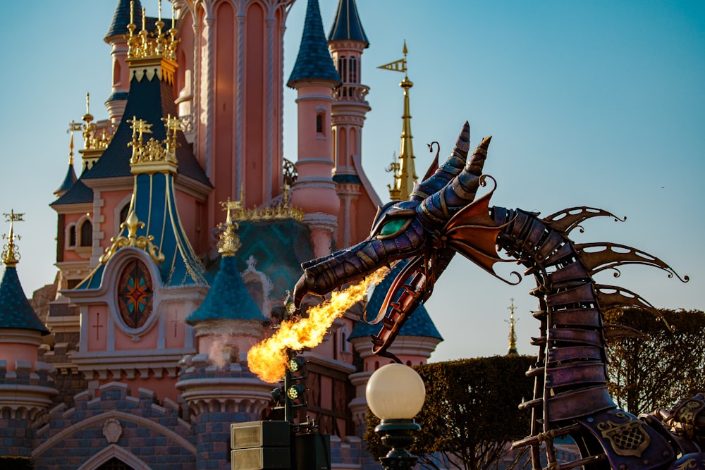 a fire breathing dragon statue in front of a castle