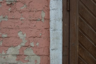 a brick wall with peeling paint and a wooden door