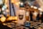 A gold skeleton trophy labeled 'Best Group' is prominently displayed on a table. Next to it, there is a white candle with the label 'Boos & Brews on the Lake.' The background features blurred, warm-toned bokeh lights adding a festive, cozy atmosphere. Several Polaroid photos are scattered on the table.