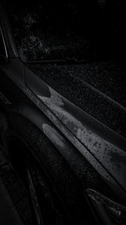 Rain droplets beading off a shiny car surface treated with water-repellent ceramic coating.