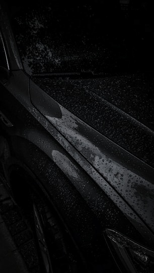 Rain droplets beading off a shiny car surface treated with water-repellent ceramic coating.