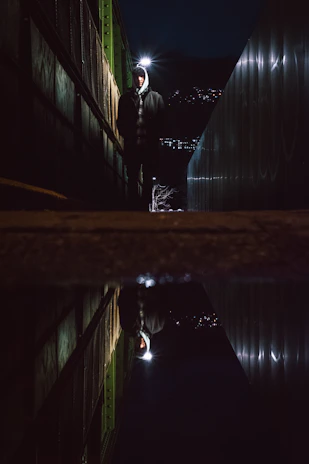 A lone warrior standing strong in a dark alley illuminated by red neon lights, embodying mental toughness.