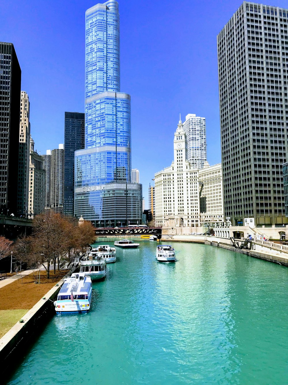 a river with several boats floating on it and tall buildings in the background