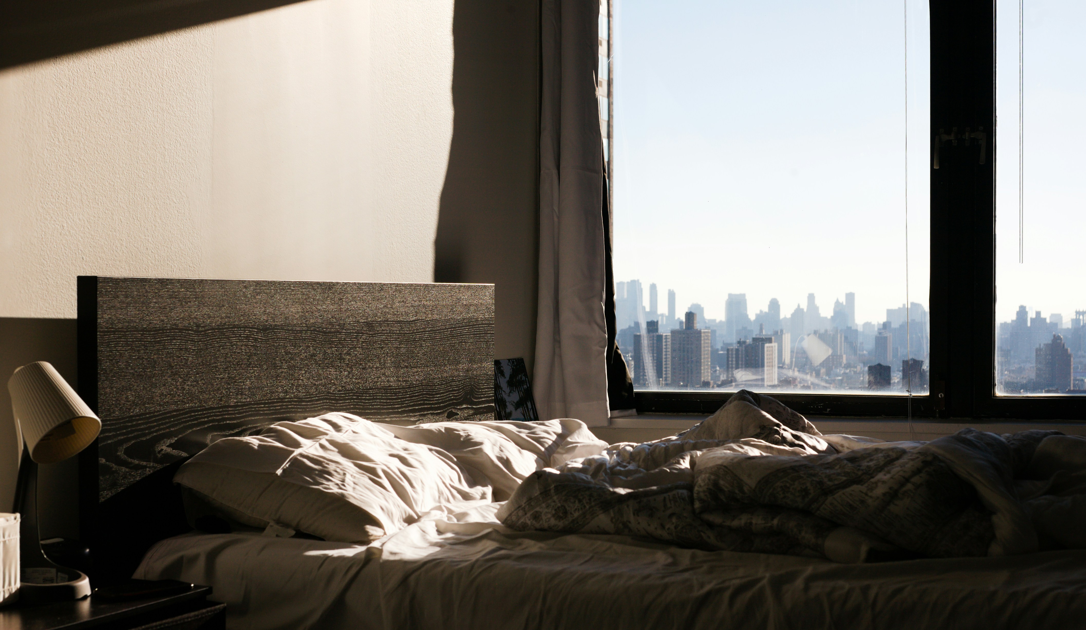an unmade bed with a view of the city