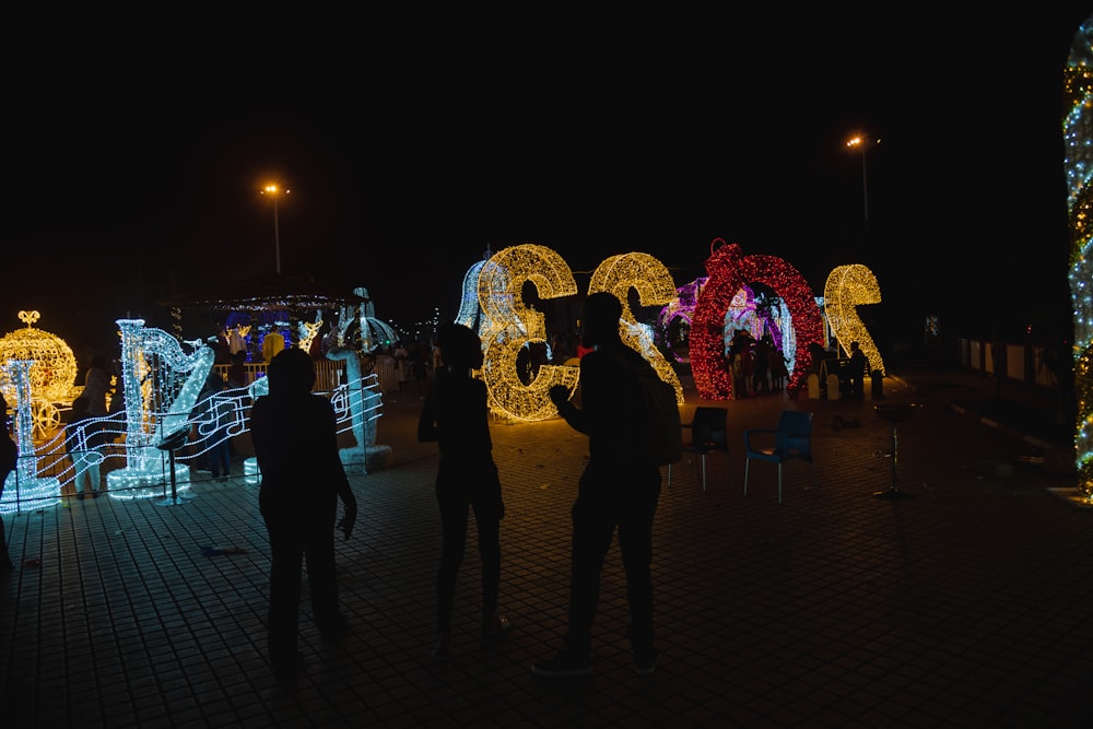 a group of people standing in front of christmas lights