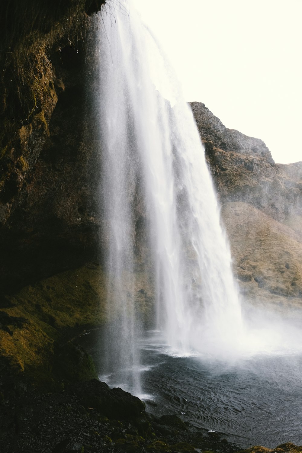 a large waterfall is pouring water into a body of water