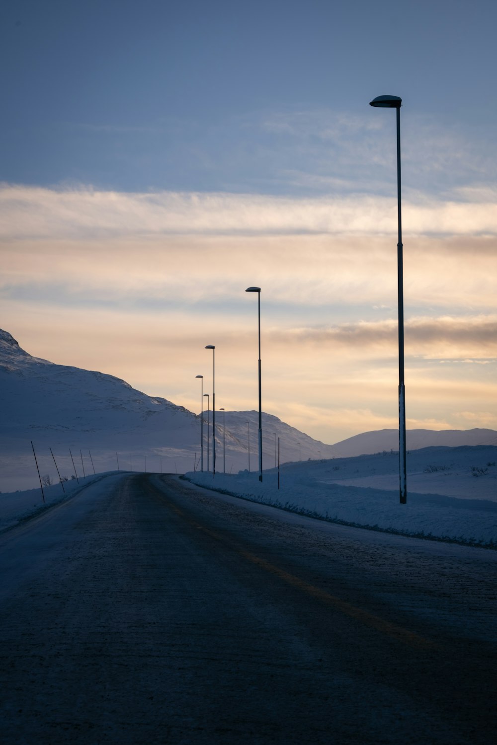 a road with street lights and snow on the ground