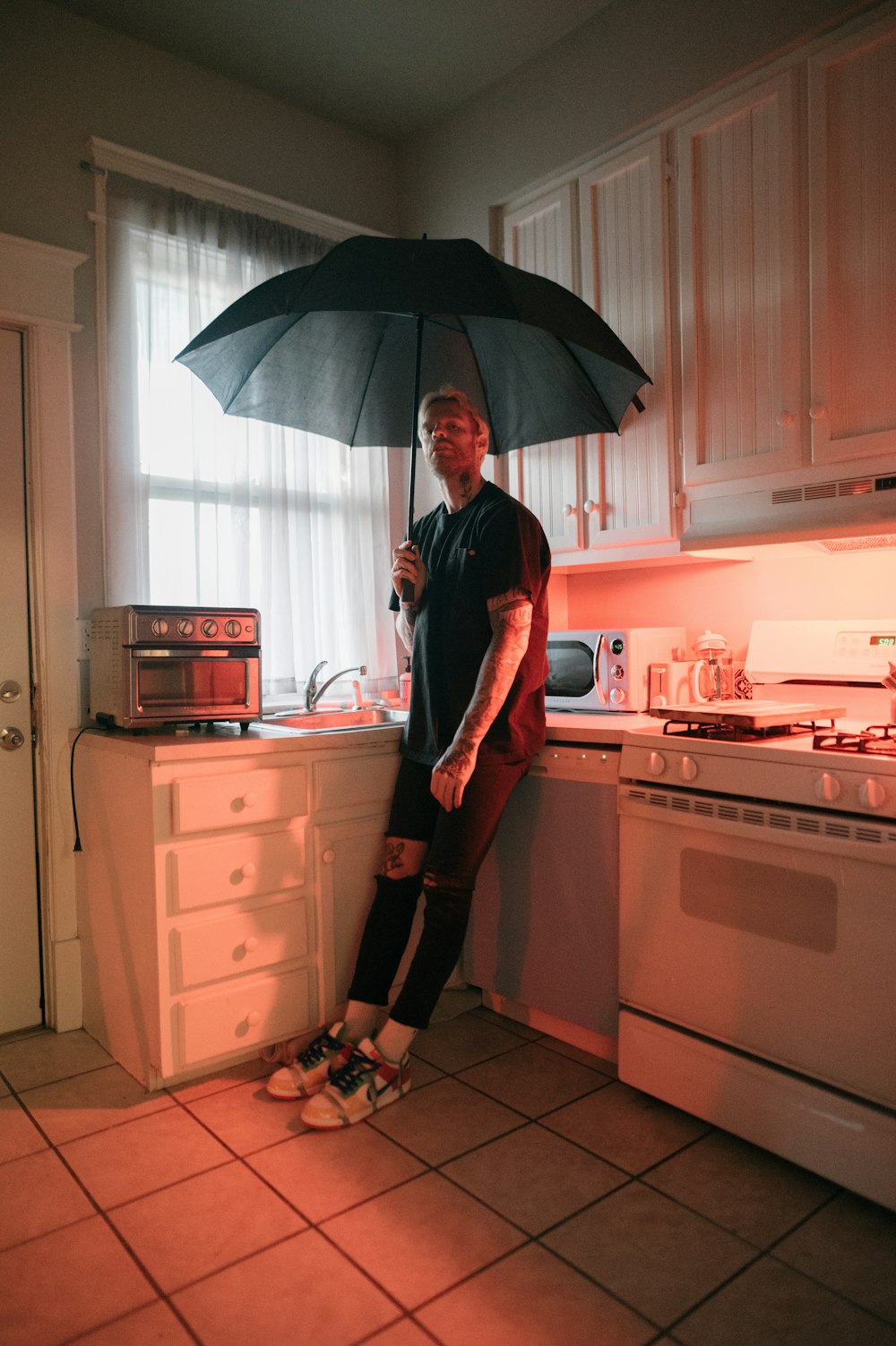a man standing under an umbrella in a kitchen