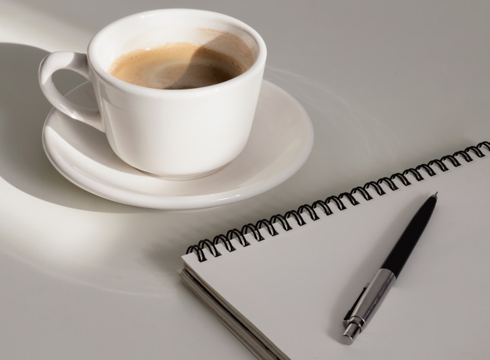 a cup of coffee and a pen on a table