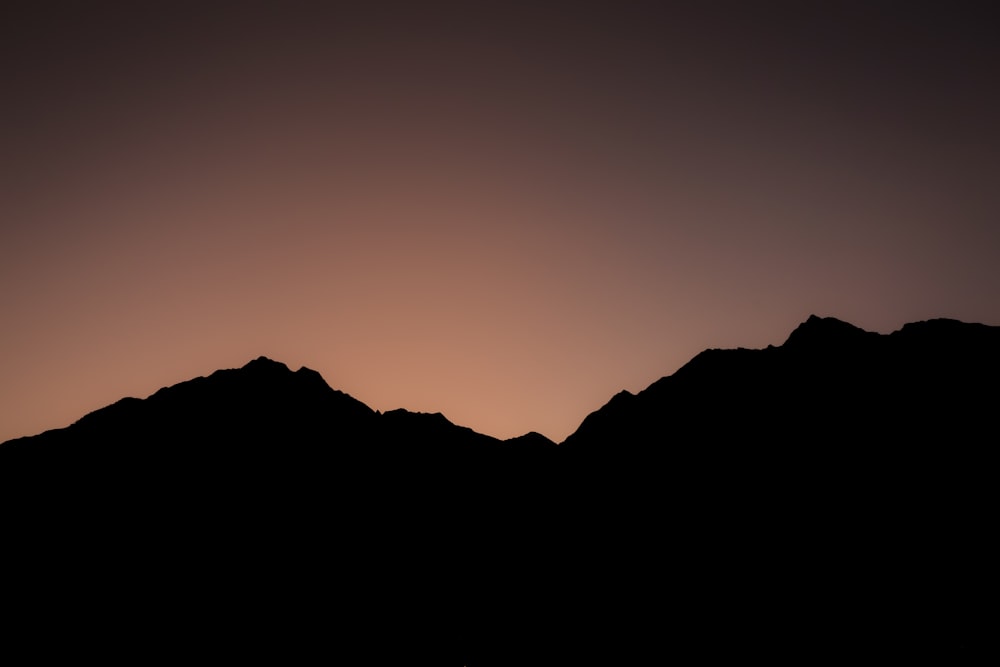 the silhouette of a mountain range at sunset