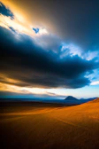 A dramatic landscape shot with rolling clouds illuminated by golden hour light