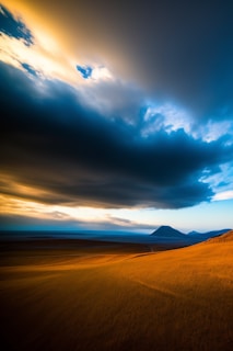 A widescreen shot of rolling agricultural fields with muted, warm colors under a moody, dramatic sky.