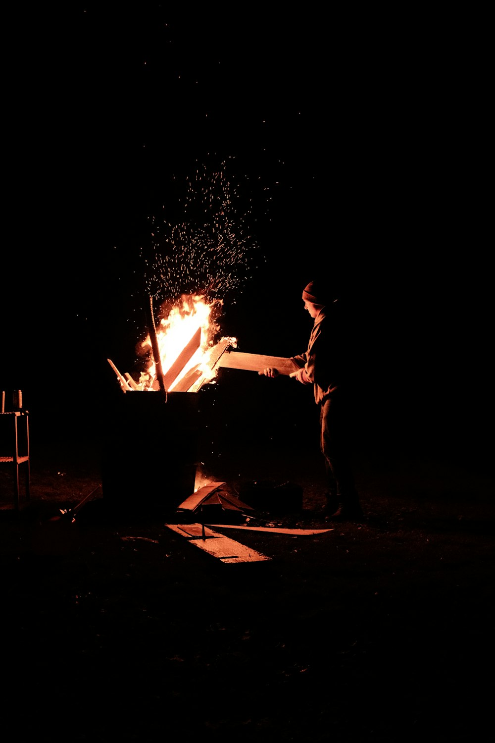 a man standing next to a fire in the dark