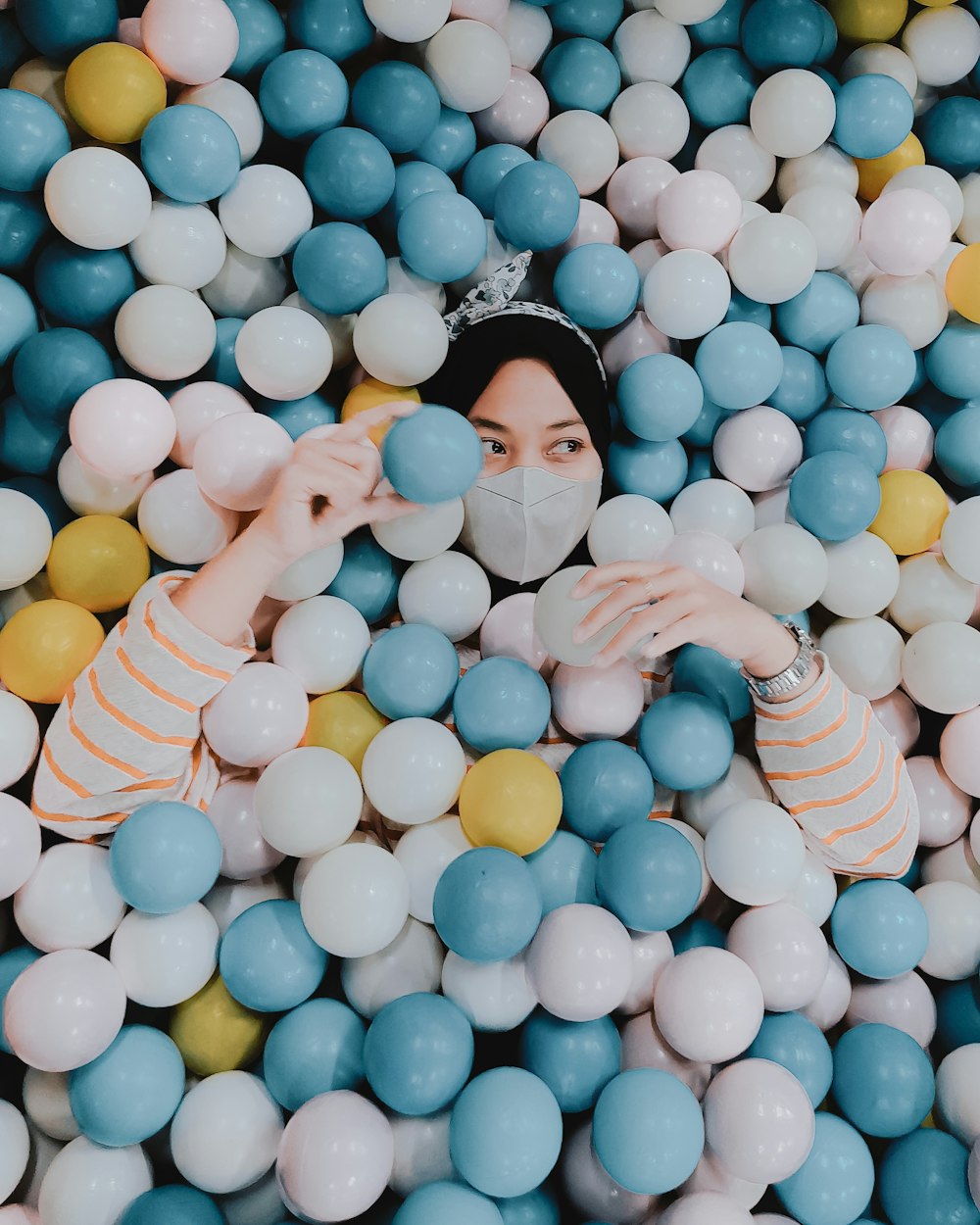 Una mujer en un pozo de bolas rodeado de globos