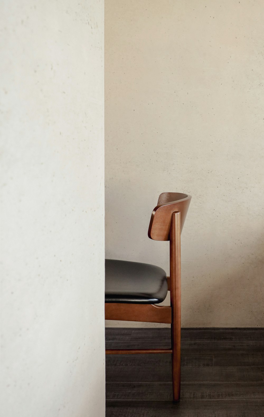 a wooden chair sitting next to a white wall