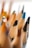 Close-up of a box filled with colorful pencils, with a blurred background of a cozy workspace.