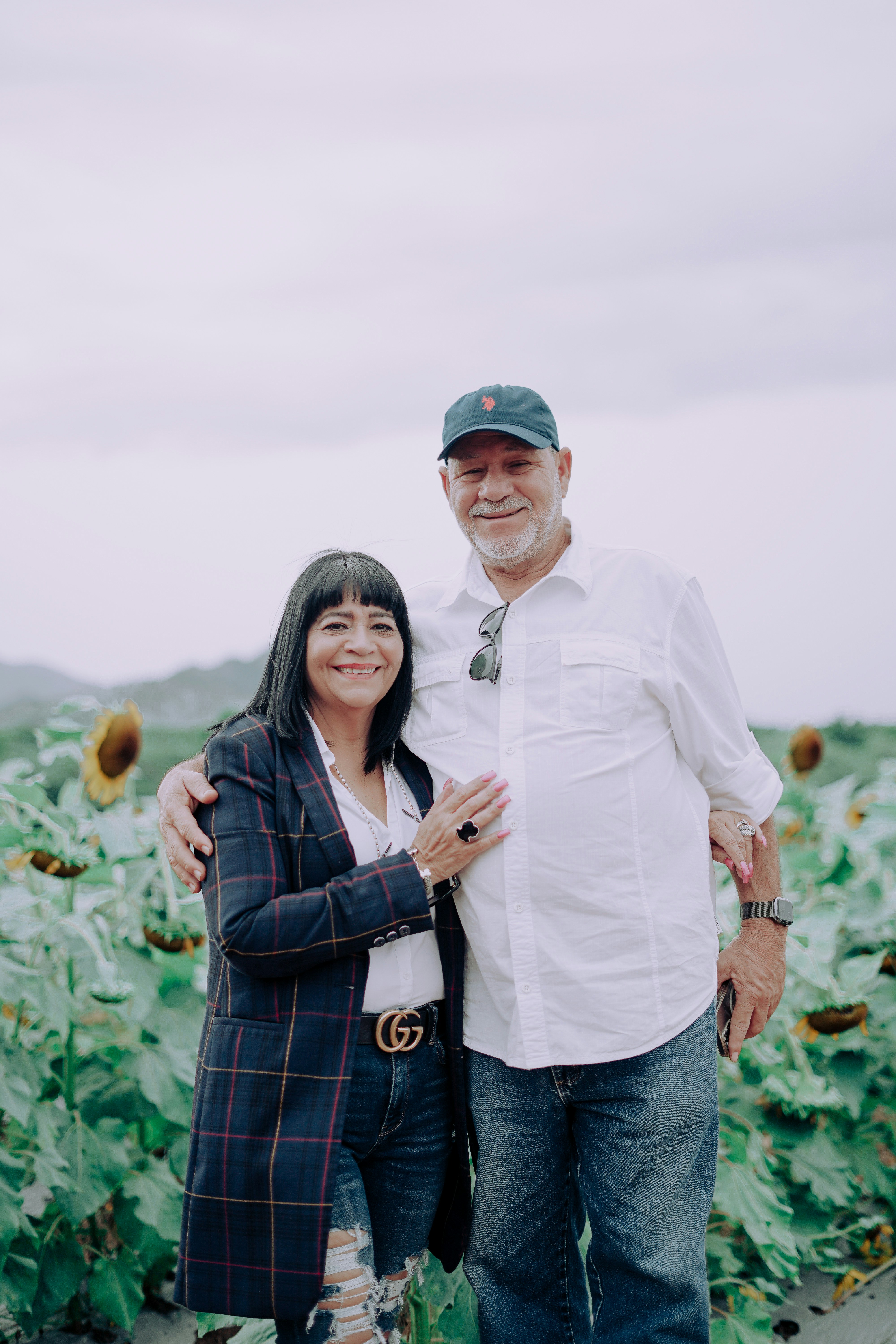 a man and a woman standing in front of a field of sunflowers