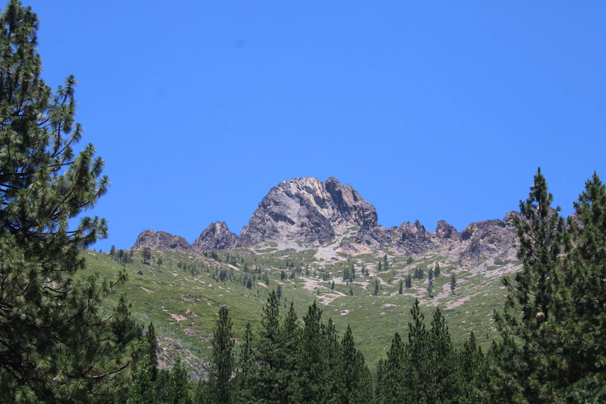 A rocky peak above green slopes and pines, seen from near Sierra City