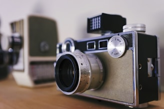 A close-up shot of a vintage camera resting on a charcoal grey surface.