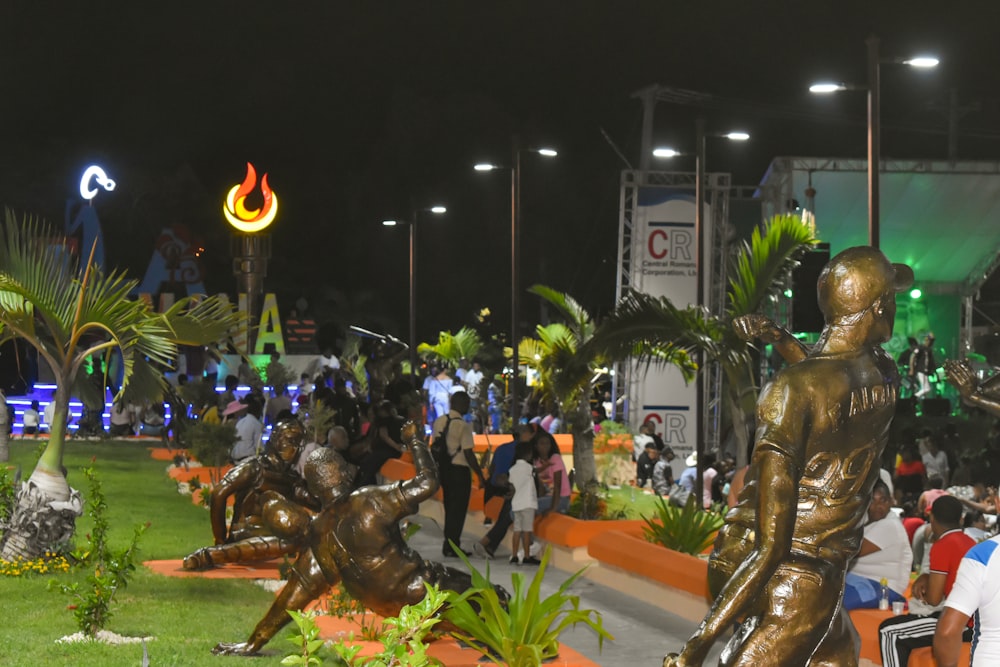 a crowd of people standing around a bronze statue