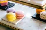 A selection of petite, pastel-colored macarons arranged artfully on a white marble surface.