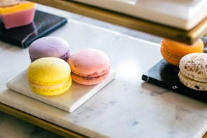 A selection of petite, pastel-colored macarons arranged artfully on a white marble surface.