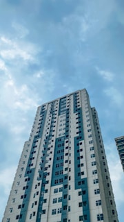 a tall white building with blue windows under a cloudy blue sky