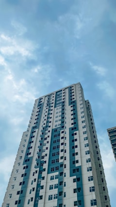 a tall white building with blue windows under a cloudy blue sky