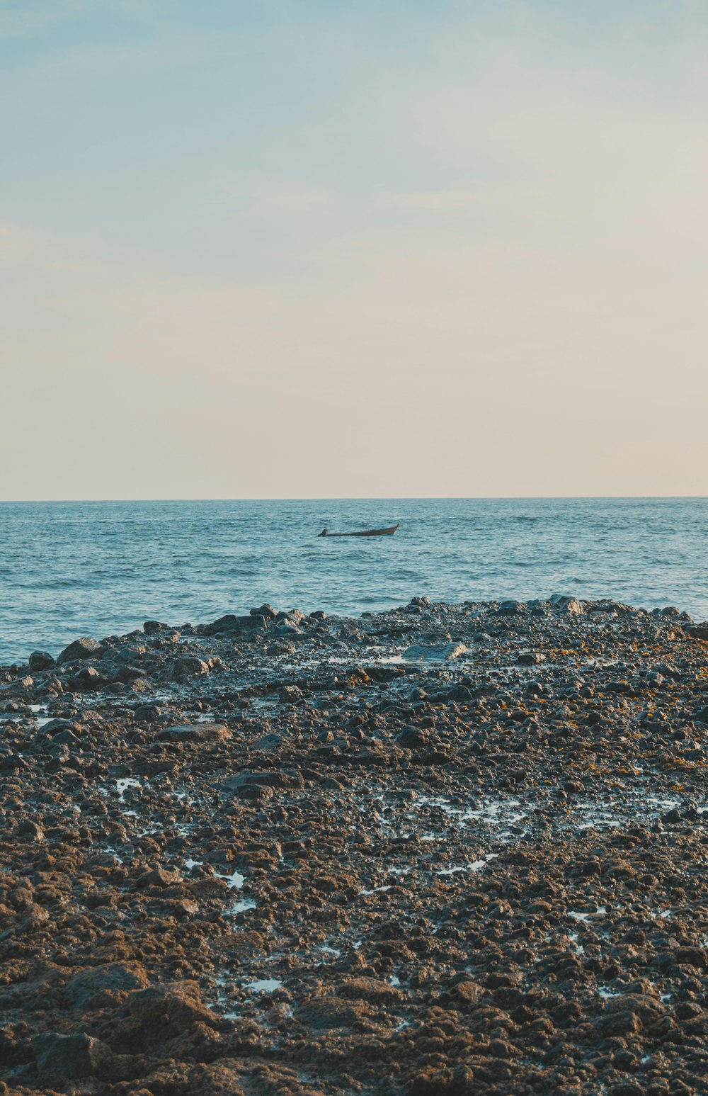 a lone boat floating in the middle of the ocean