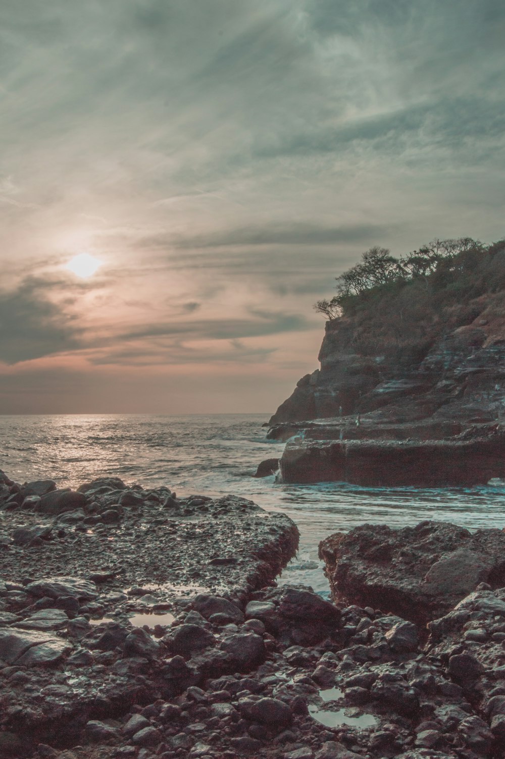 the sun is setting over a rocky beach