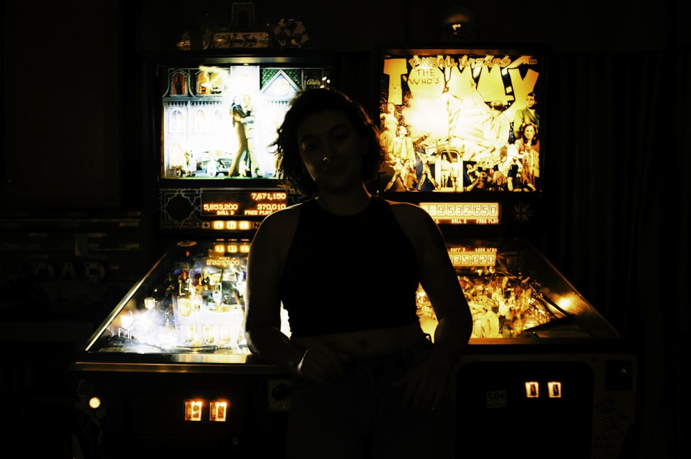 a woman standing in front of a pinball machine