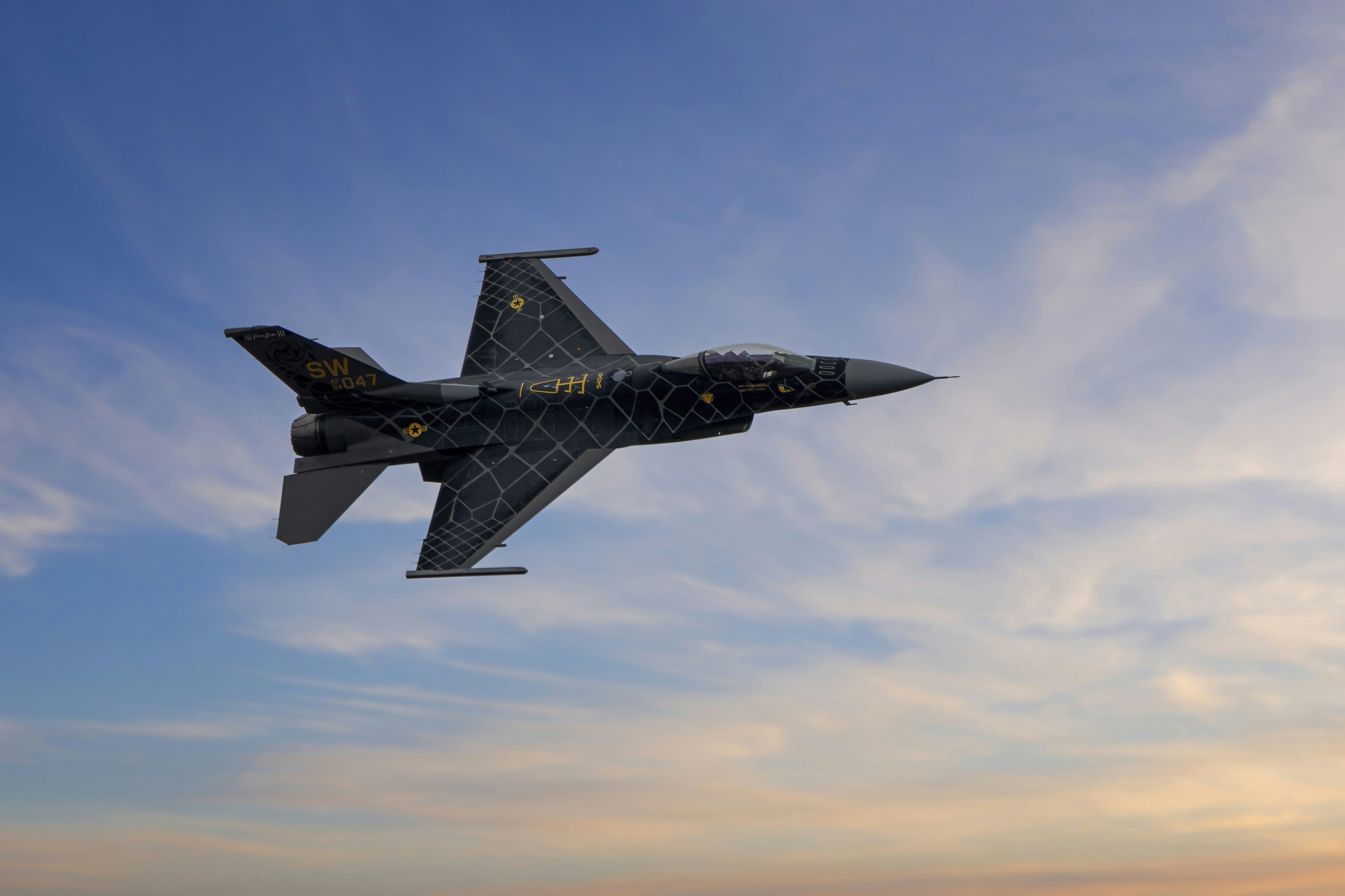 a fighter jet flying through a cloudy blue sky