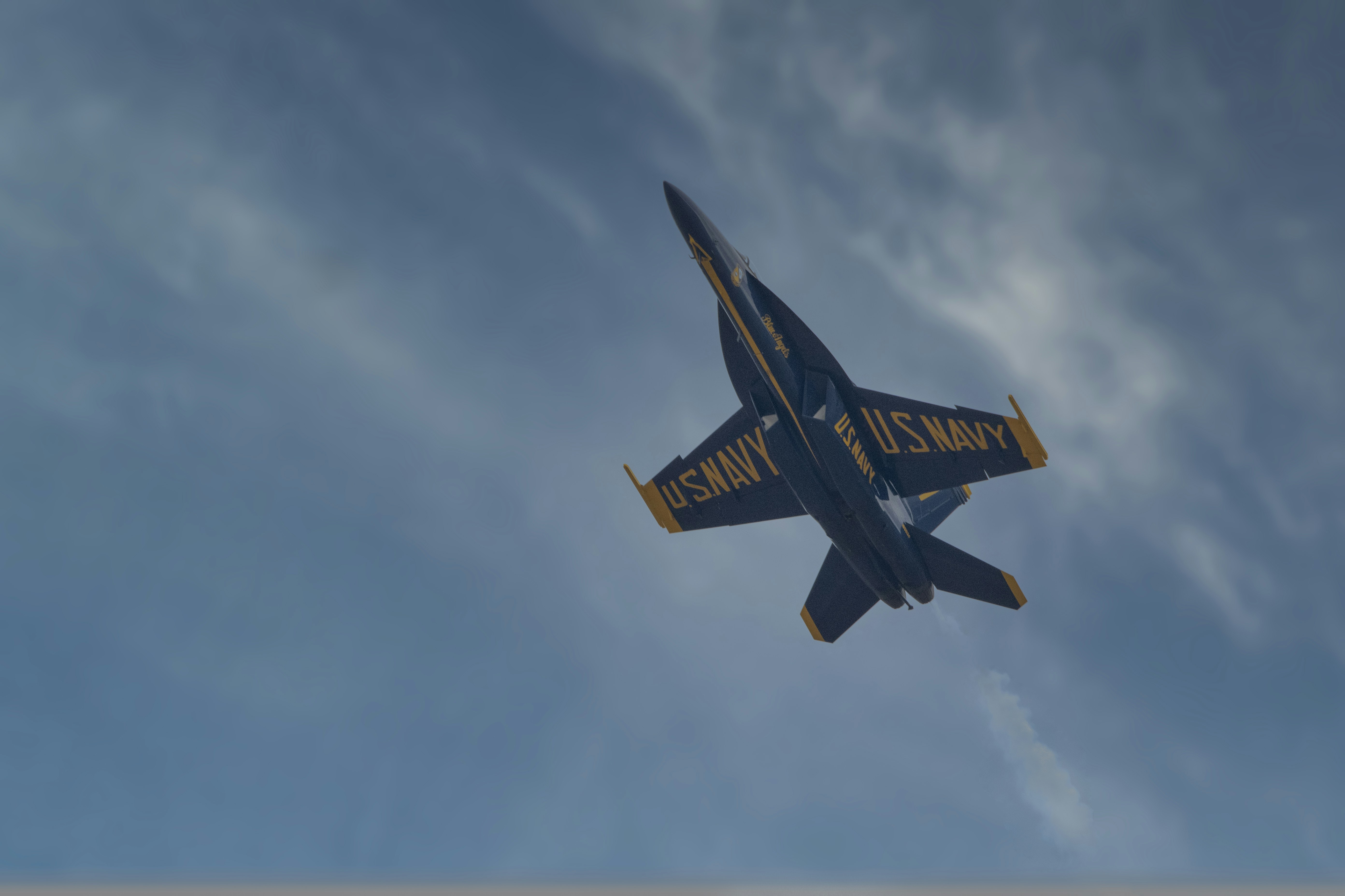 a blue and yellow plane flying in the sky