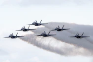 a formation of fighter jets flying through a cloudy sky