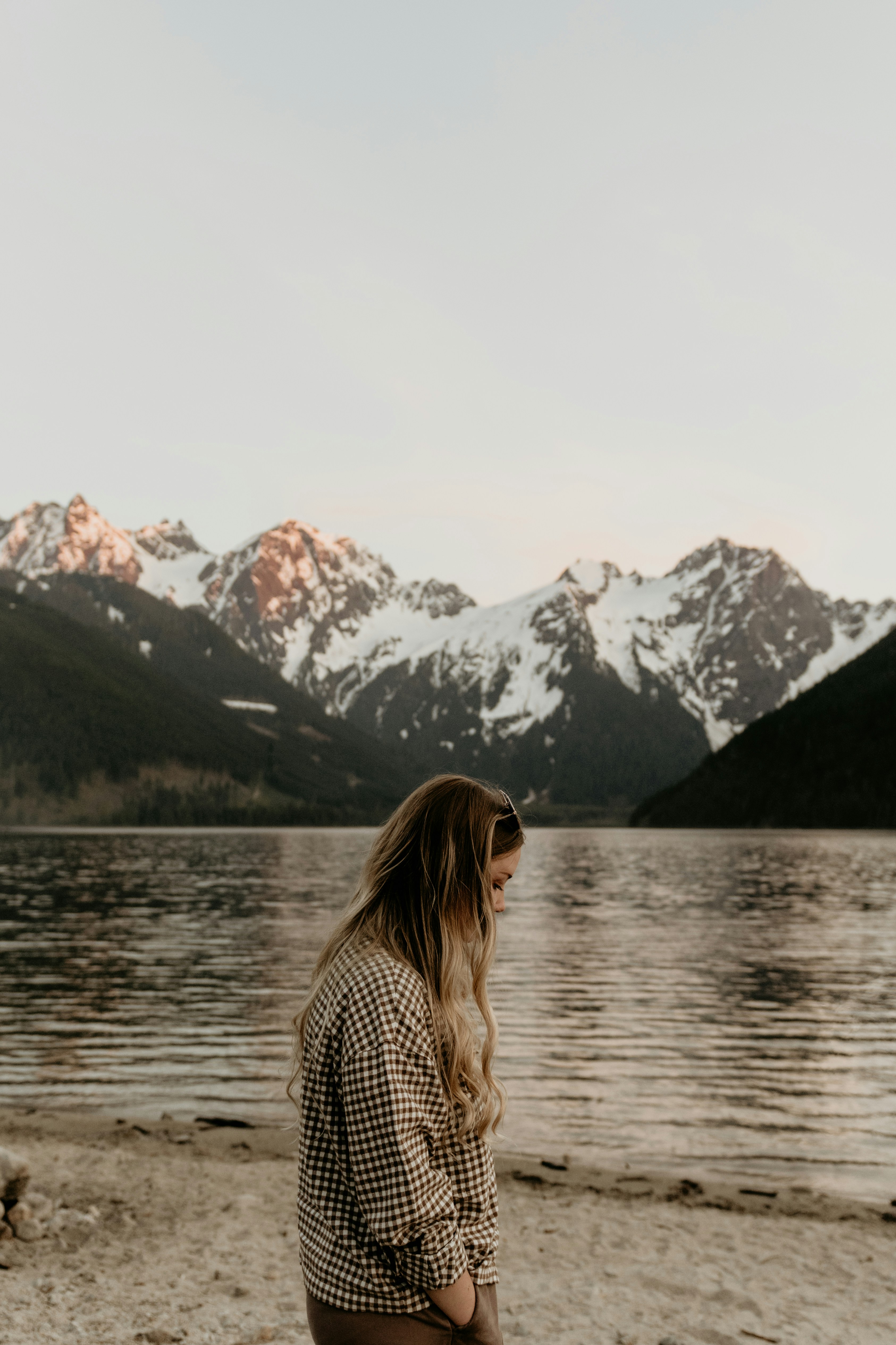 a woman standing on a beach next to a body of water
