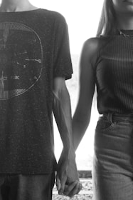 An intimate black-and-white photo of a couple holding hands, highlighting their connection.