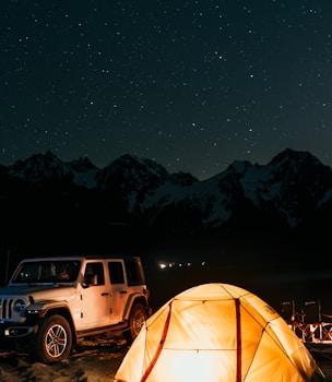 a tent and a jeep parked in front of a mountain range