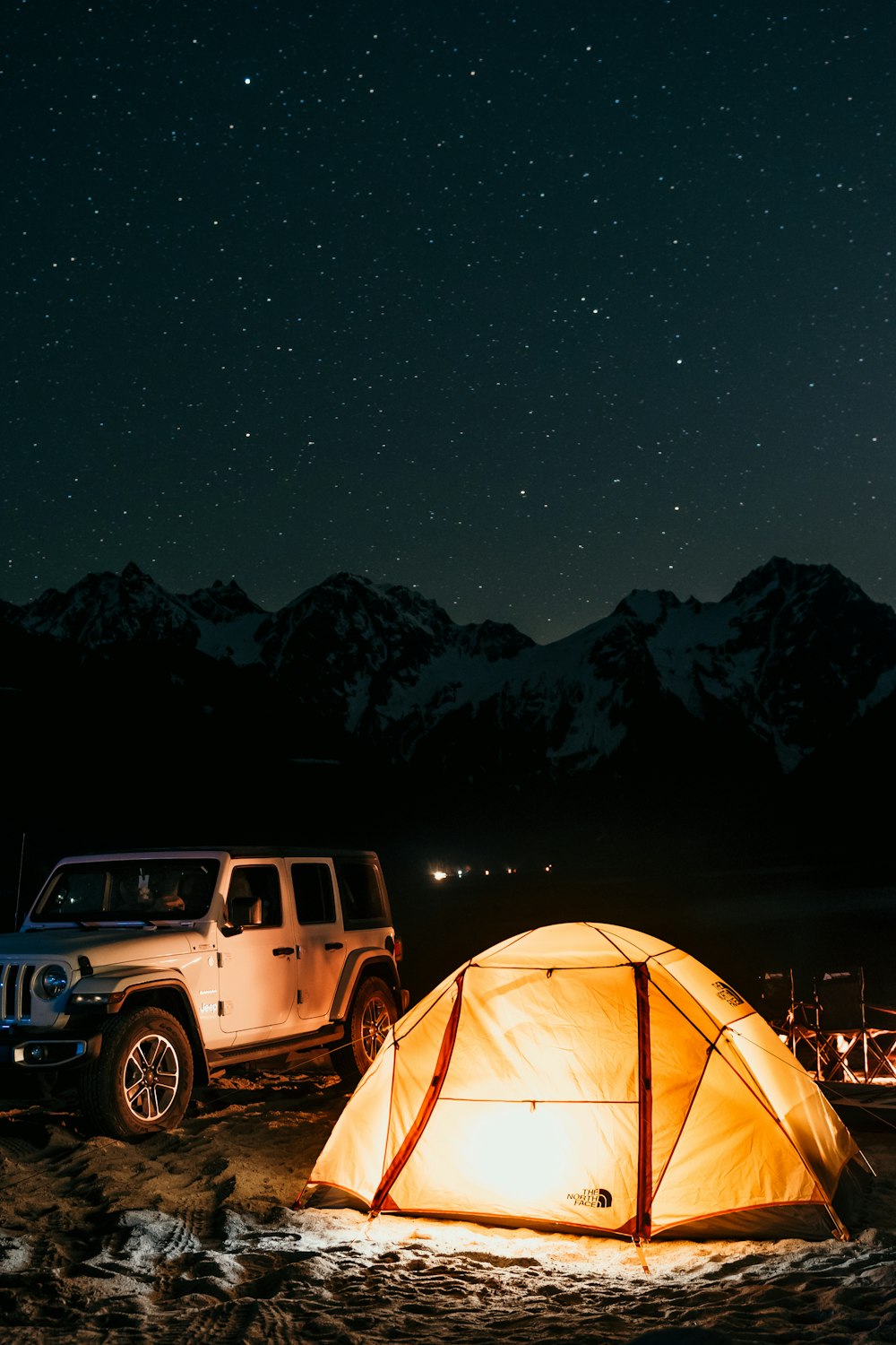 a tent and a jeep parked in front of a mountain range