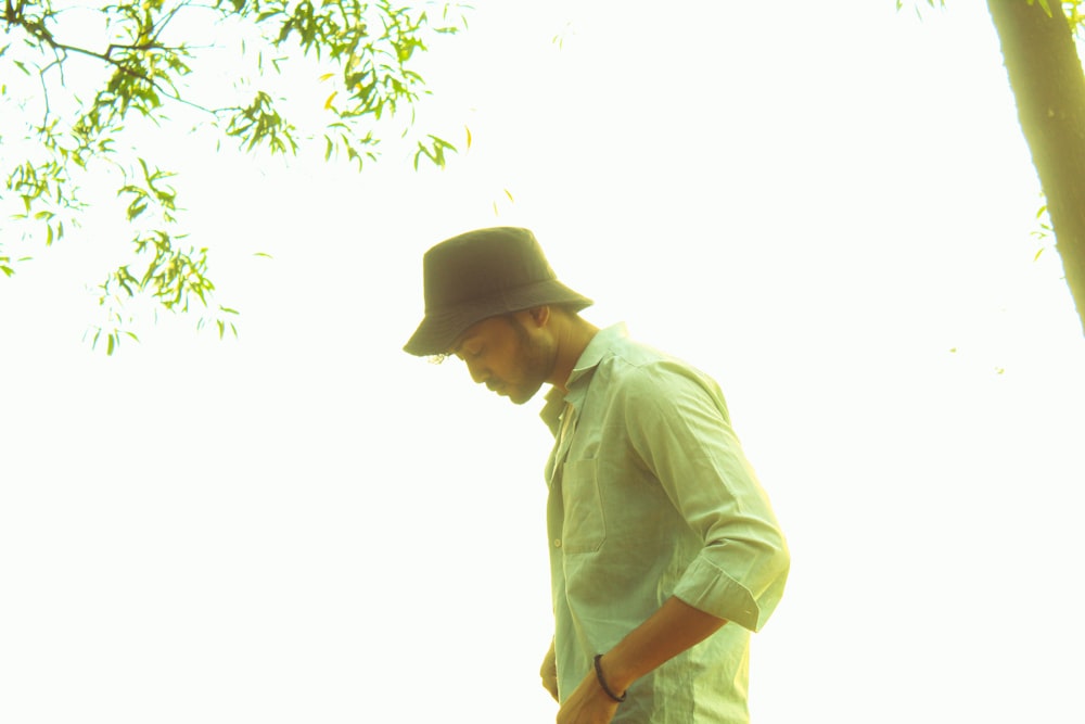 a man in a hat standing next to a tree