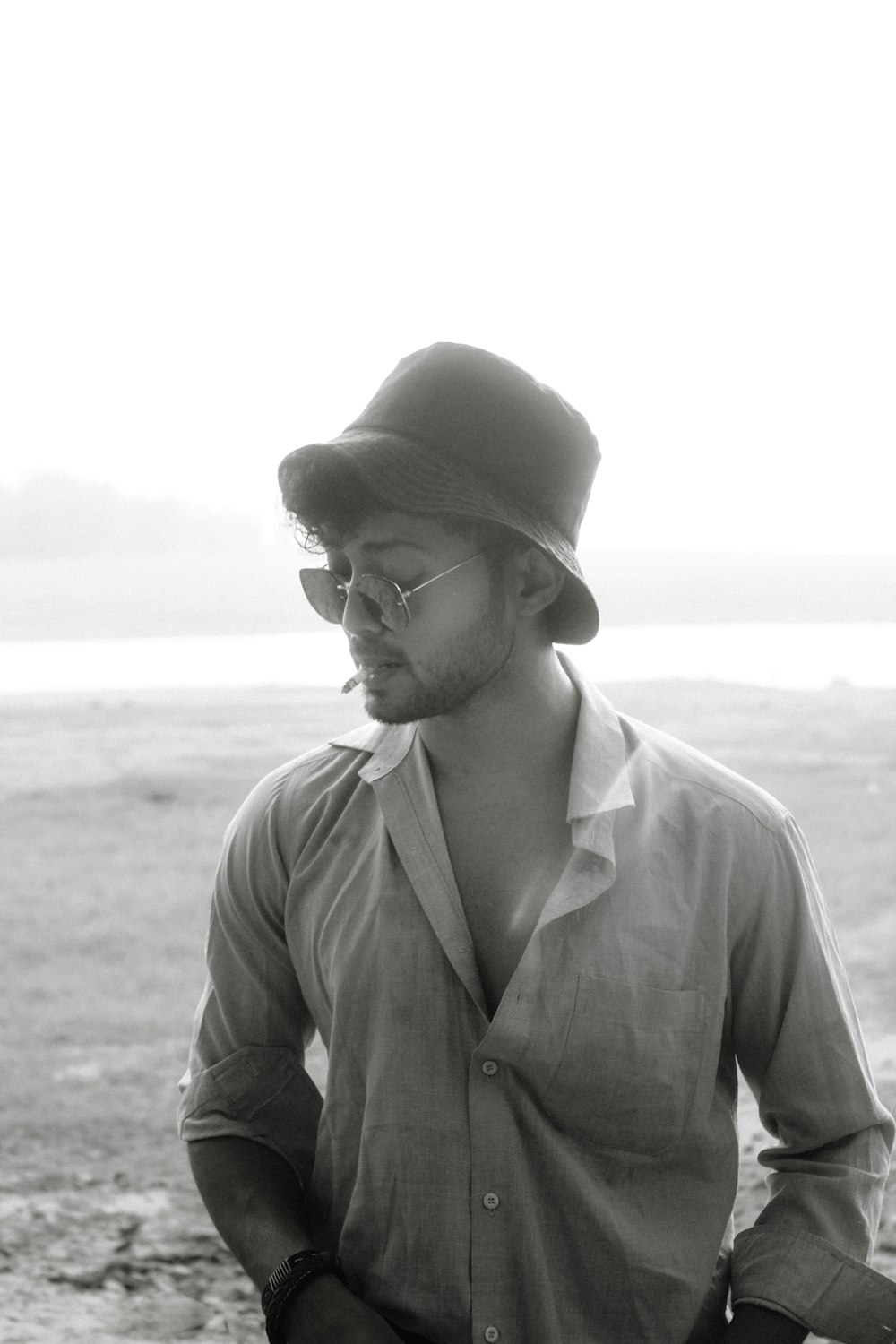 a man wearing a hat and glasses standing in a field