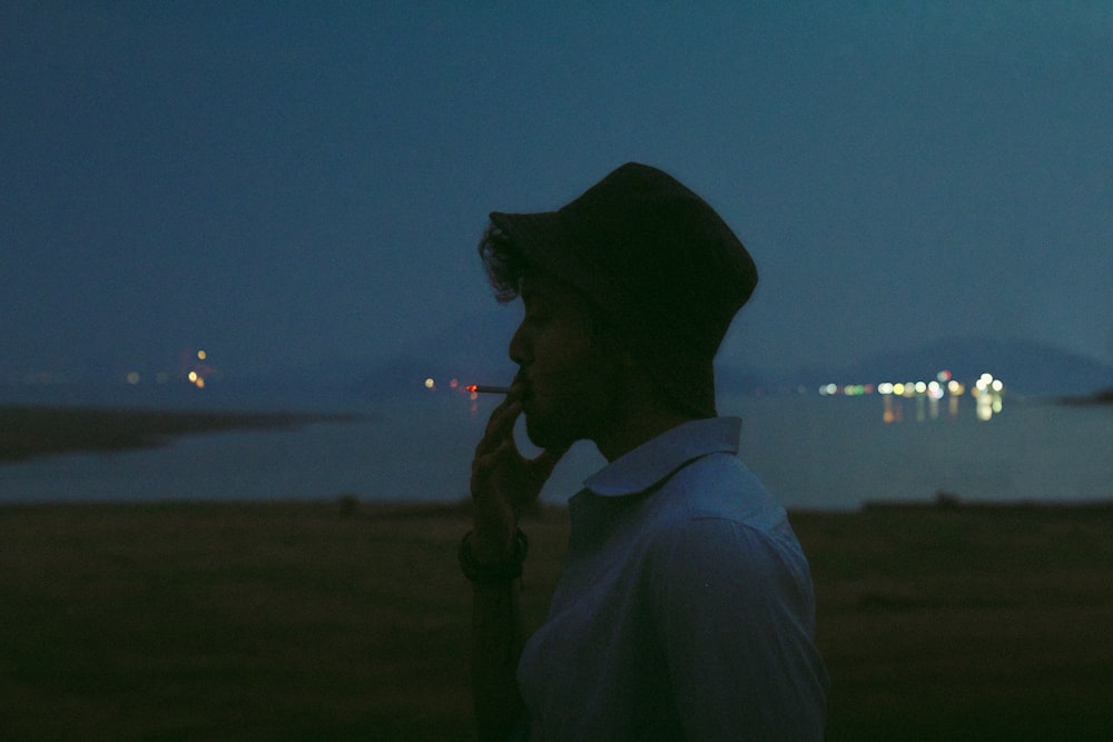 a man standing in front of a body of water at night