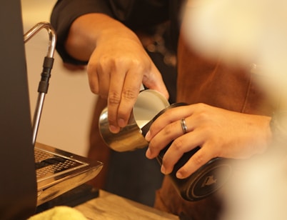 a person pouring something into a cup on a table