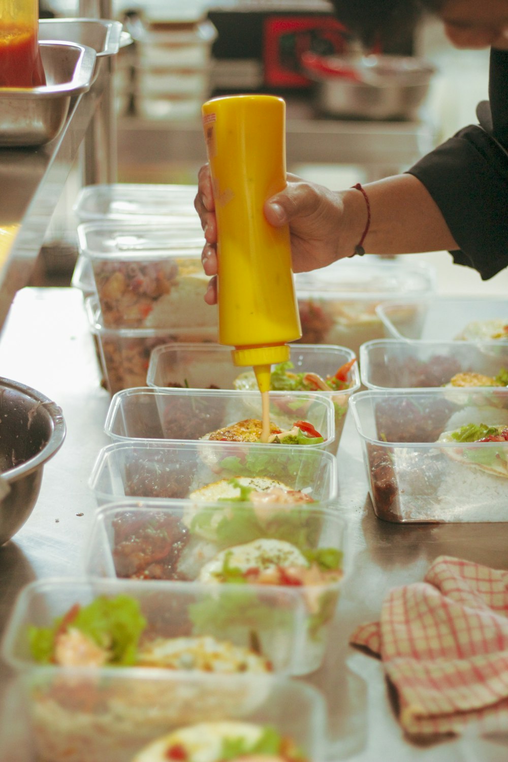 a person pouring dressing into a container of food