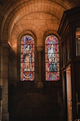 Volunteers cleaning stained glass windows inside a church.
